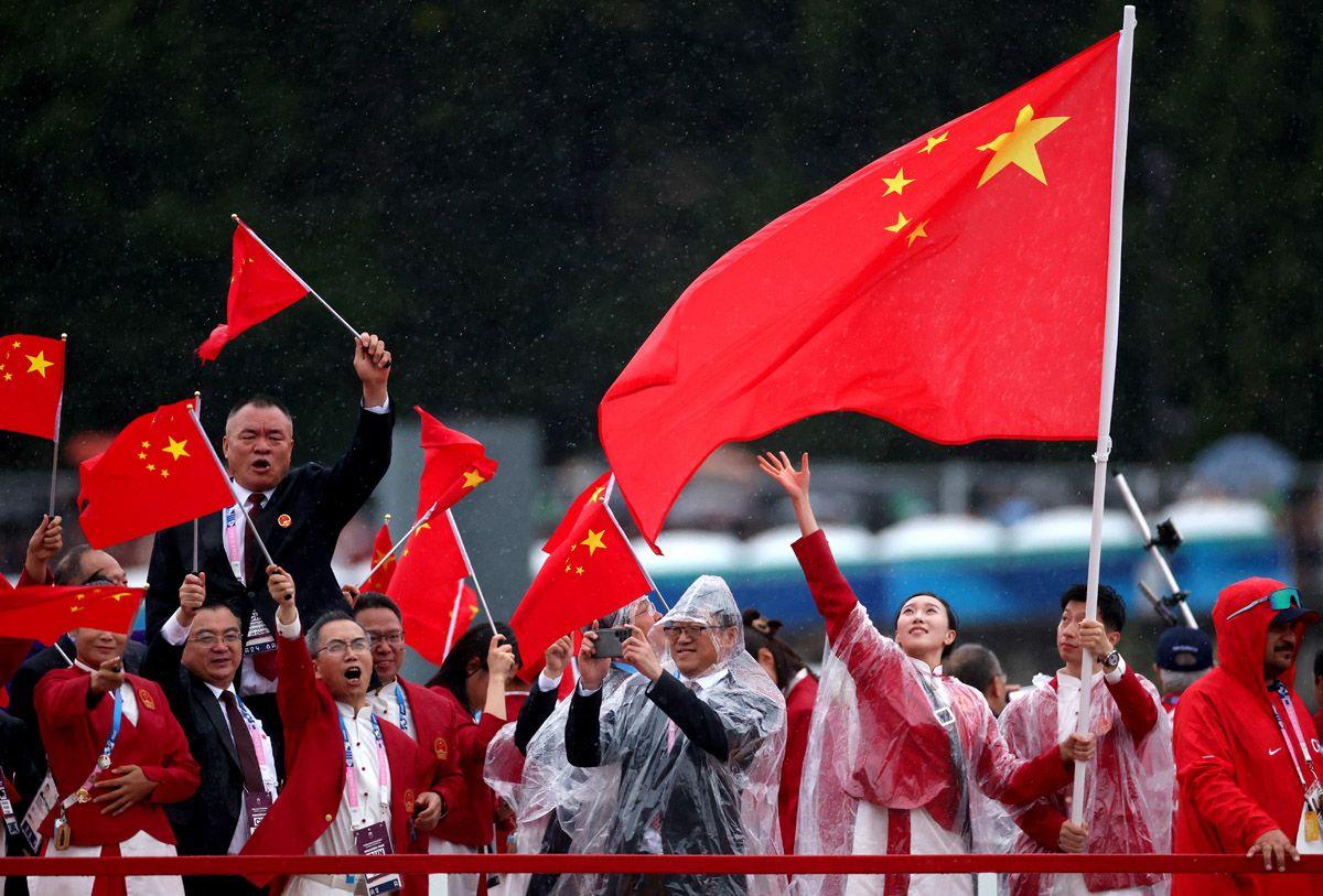 Flagbearers Yu Feng of China and Long Ma of China, wave their flag on the team boat along the River Seine