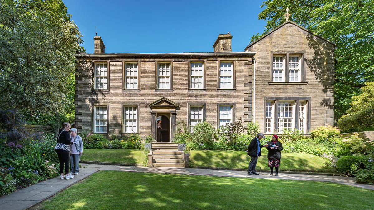 Visitors standing on the lawn outside the Brontë Parsonage Museum in Haworth