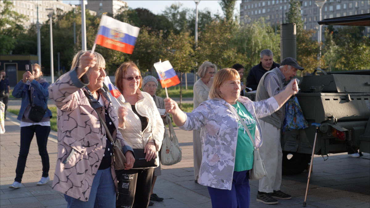 Three women hold Russian flags and smile