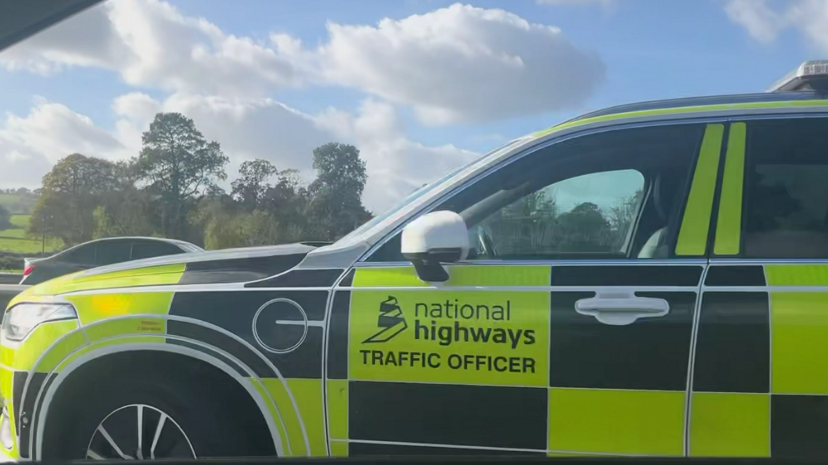 A photo taken through a car window of a National Highways traffic officer branded vehicle parked in the right hand lane of the southbound M5.