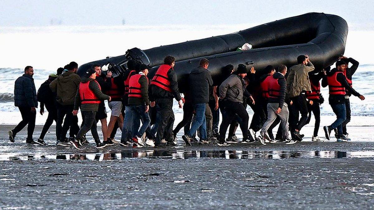 Migrants carry aboat towards the water before they attempt to cross the Channel illegally to Britain, July 2022