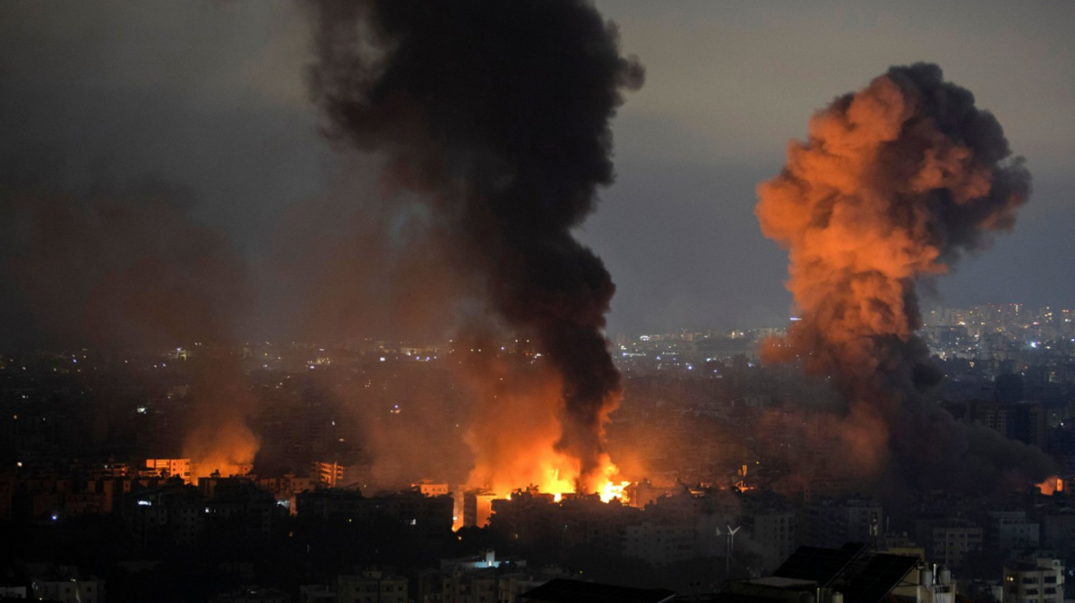 Smoke rises as a result of an Israeli airstrike at Dahieh Saint Therese area in the southern suburb of Beirut. An orange flash of fire can also be seen in the foreground