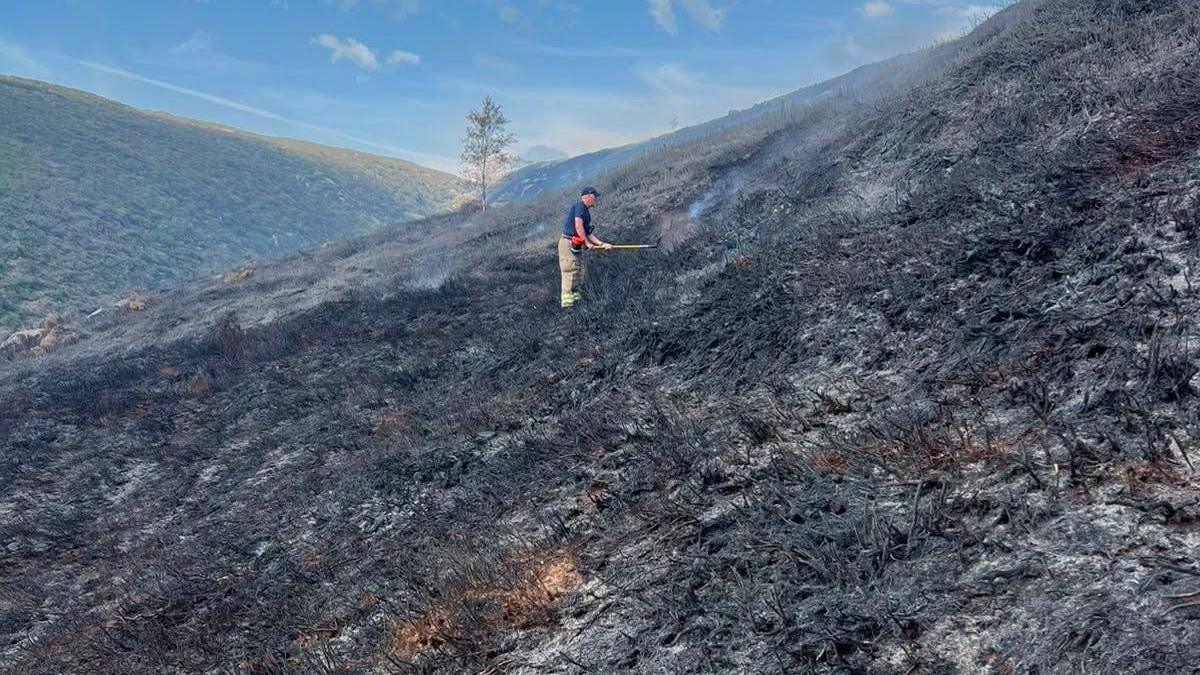 A firefighter damping down hot spots following a moorland wildfire on Tintwistle Moor, above Woodhead Road in Glossop, Derbyshire.