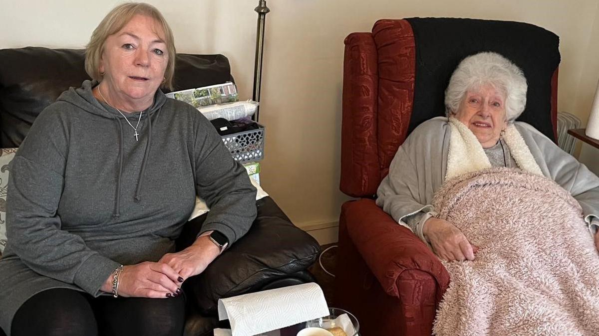 Marianne is seen sitting on the couch next to Margaret who is in a red armchair. Both are looking towards the camera.