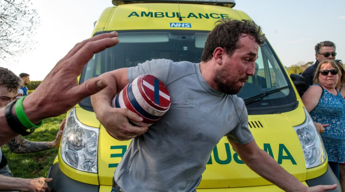 A man carrying a keg runs past an ambulance