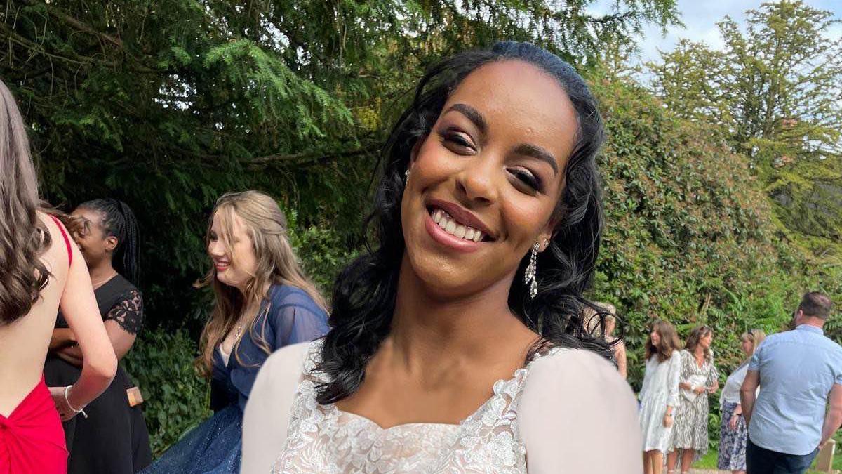 Afaf Ahmed wearing a white dress and silver earrings in a garden