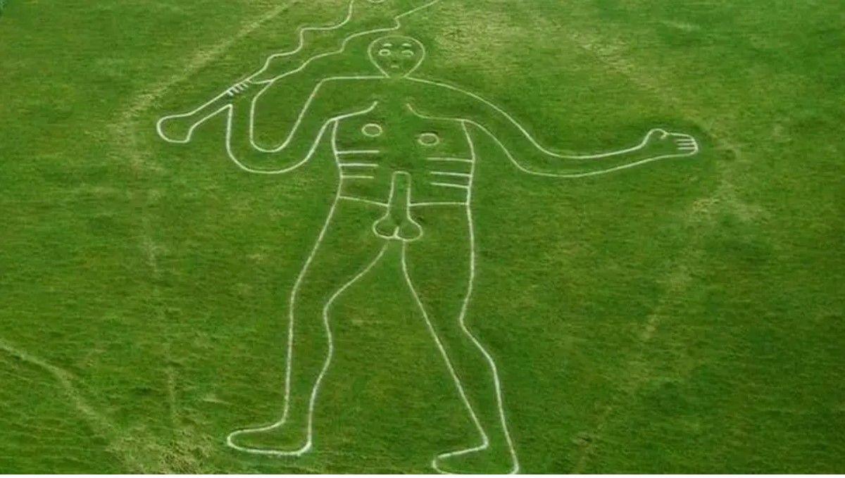 Green grassy hill with giant chalk figure - the Cerne Abbas Giant - carved into it.