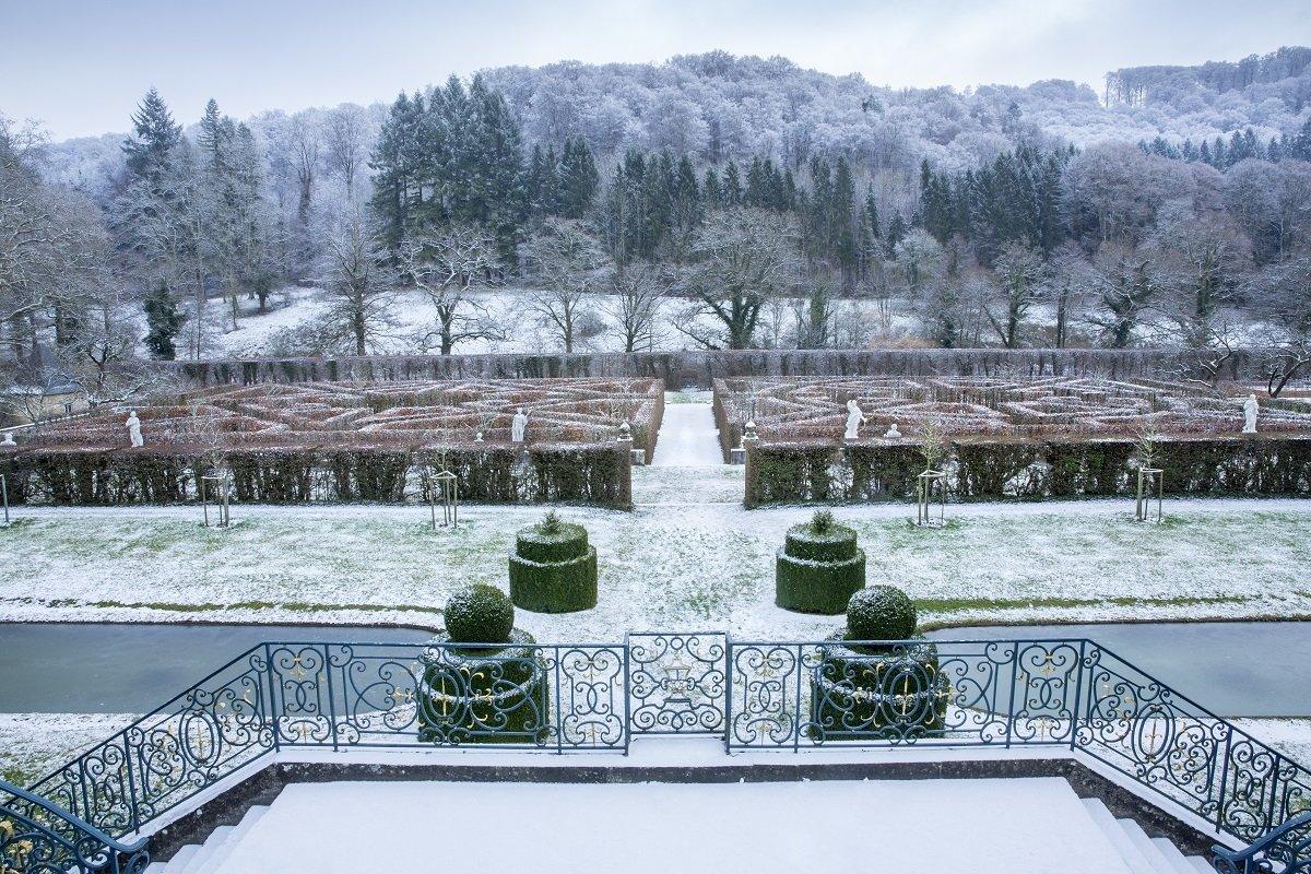 A snow-covered landscape showing a garden maze in front of a forest