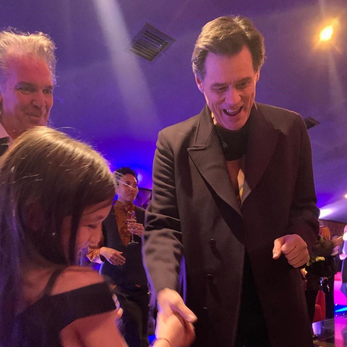 Actor Jim Carrey is shaking hands with Ruby while looking at her painting