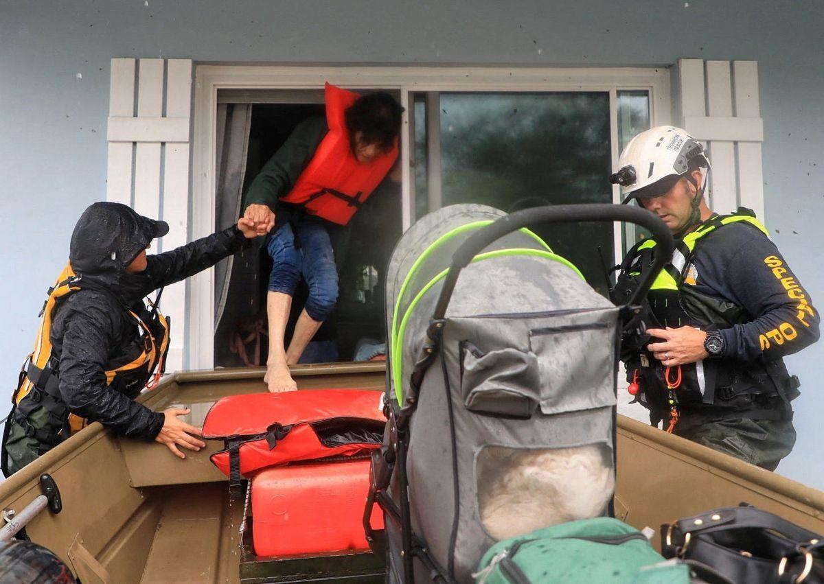 Volusia Sheriff's Special Ops team members in rescue gear help a resident in a life vest into a boat out their window in South Daytona, Florida, U.S., October 10, 2024.