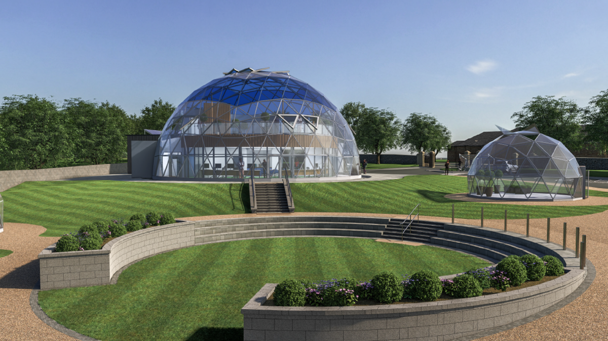 A design drawing of a geodesic dome that will form part of an urban farm in Derry. It is glass fronted and has steps at its front leading down to a grassy areas. a smaller dome sits to its right.