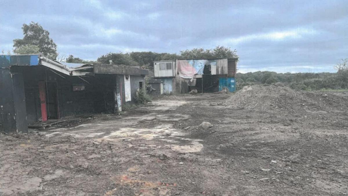 Damaged land, with piles of burnt waste and charred buildings