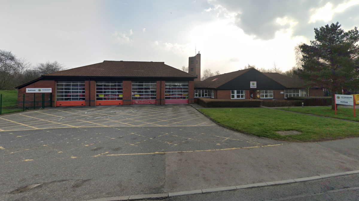 A single-storey fire station building with four large doors for engine access and tree to the right 