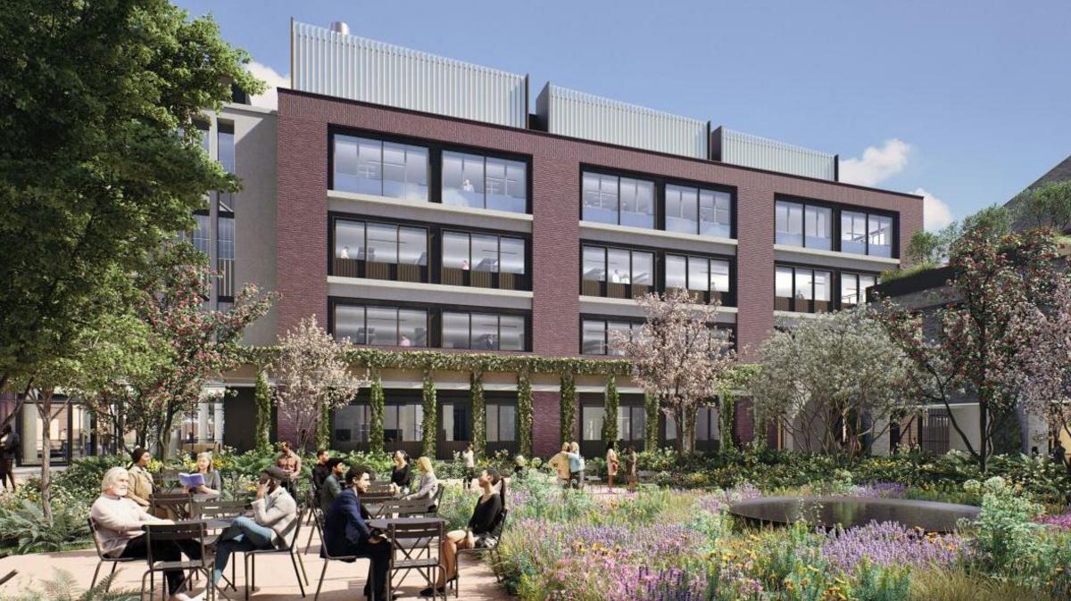 An artist's impression of a redeveloped Trinity Hall Farm Industrial Estate. Along the back are four storey red brick buildings with large picture windows. in front is a garrden packed with plants and flowers, a pond on the right And on the left is a patio with people sitting a bistro tables. 