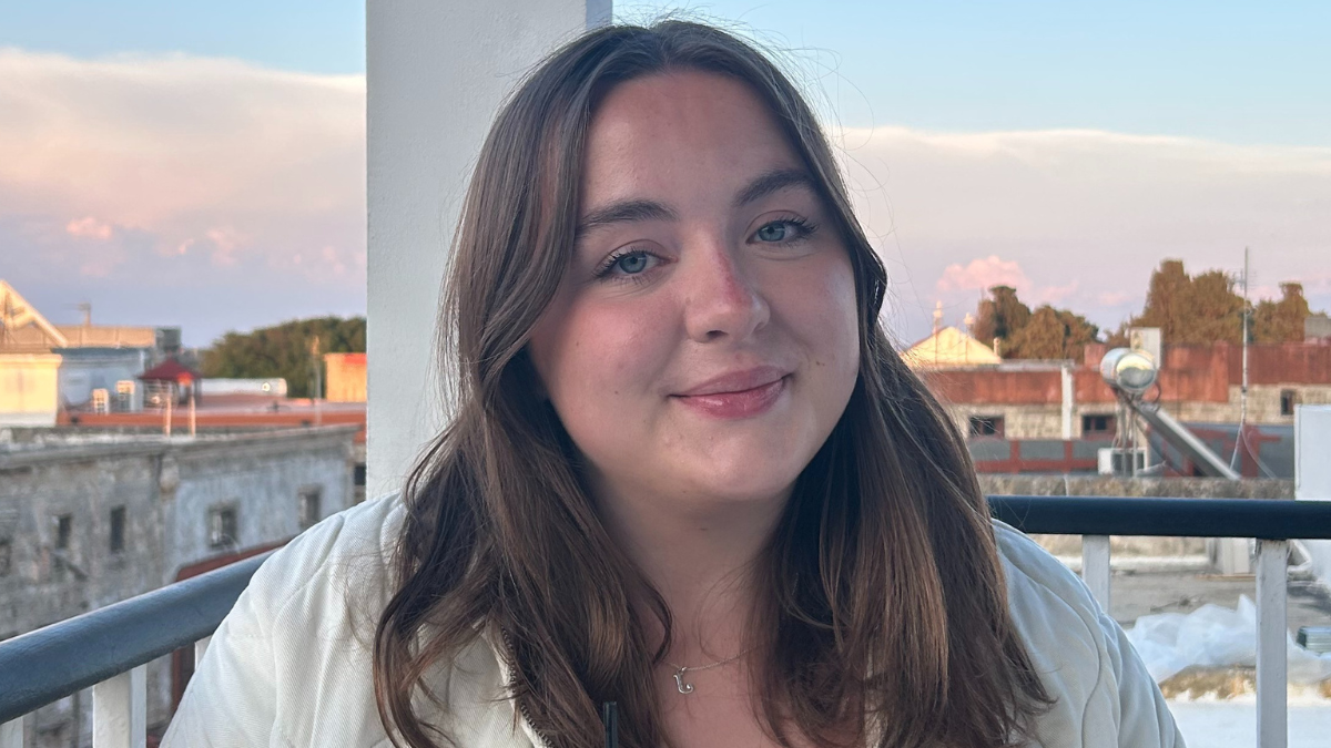 Jenny Smart smiling at the camera has brown hair, blue eyes and is wearing a white top.