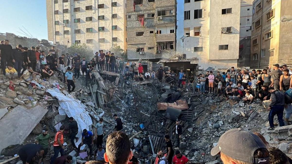 Dozens of Palestinians gather around the crater left by an Israeli strike on a on a building in Gaza City