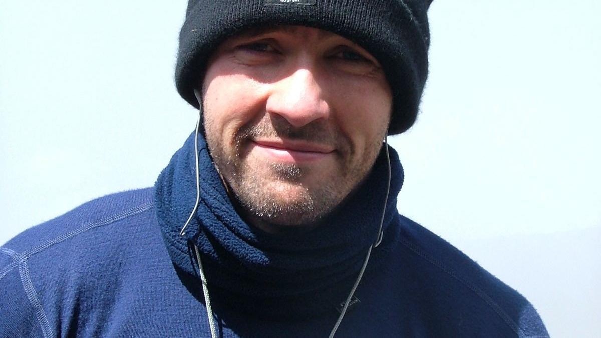 Paul Doyle, in his early 20s, pictures wearing a black woolly hat and a blue fleece with a bright blue sky in the background. 