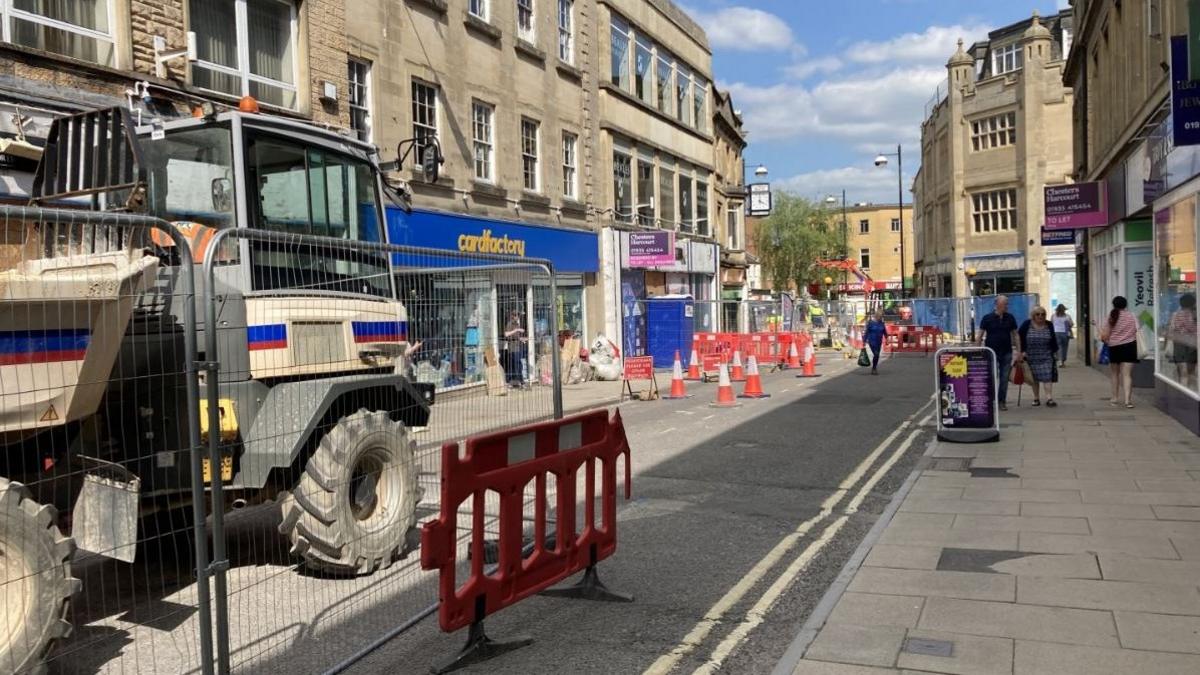 The town centre of Yeovil with shoppers walking down the street surrounded by cones and fences and roadworks and construction machinery