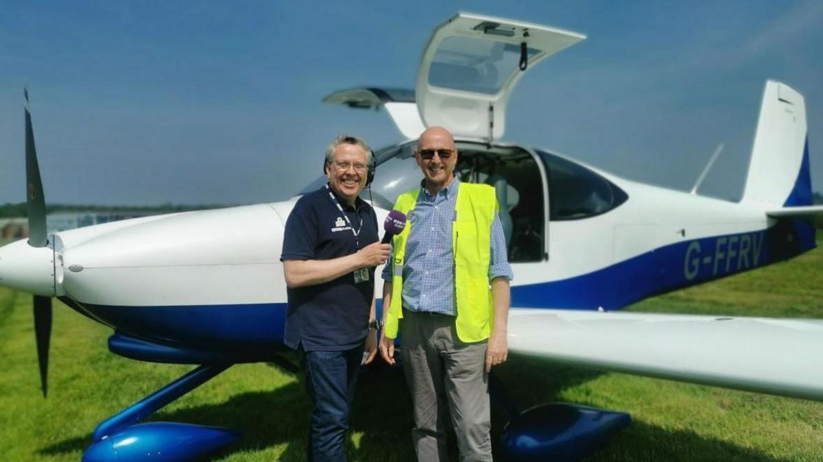 Two men standing next to a plane