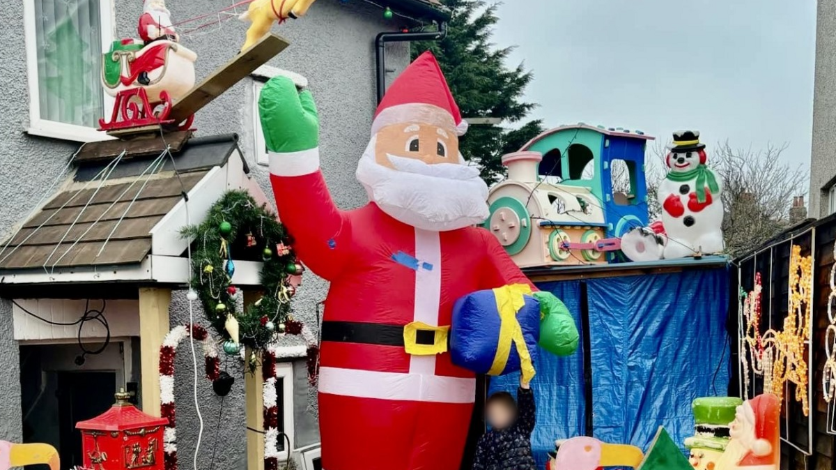 A wide shot of the Condor Grove Christmas lights display, which includes a snowman, a wreath, a sleigh, and a giant inflatable Santa waving