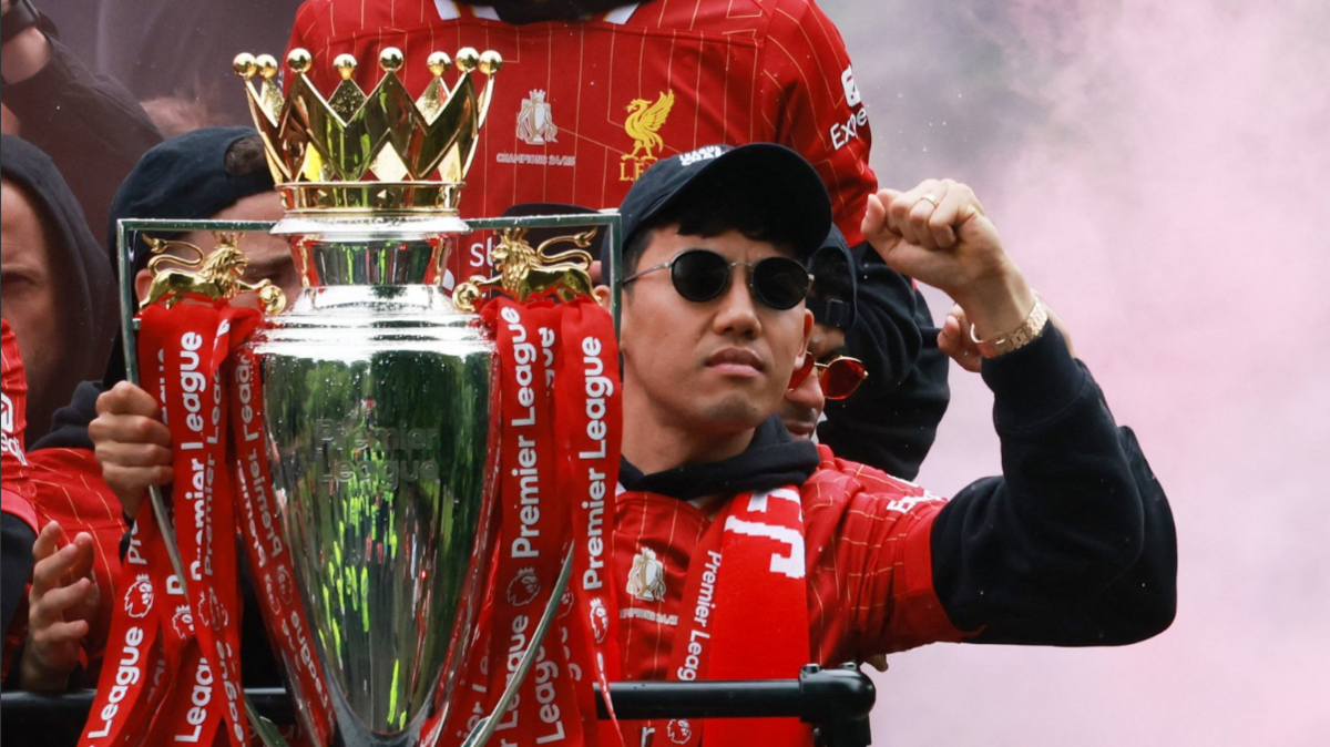 A Liverpool player wearing shades clutches the trophy onboard the bus