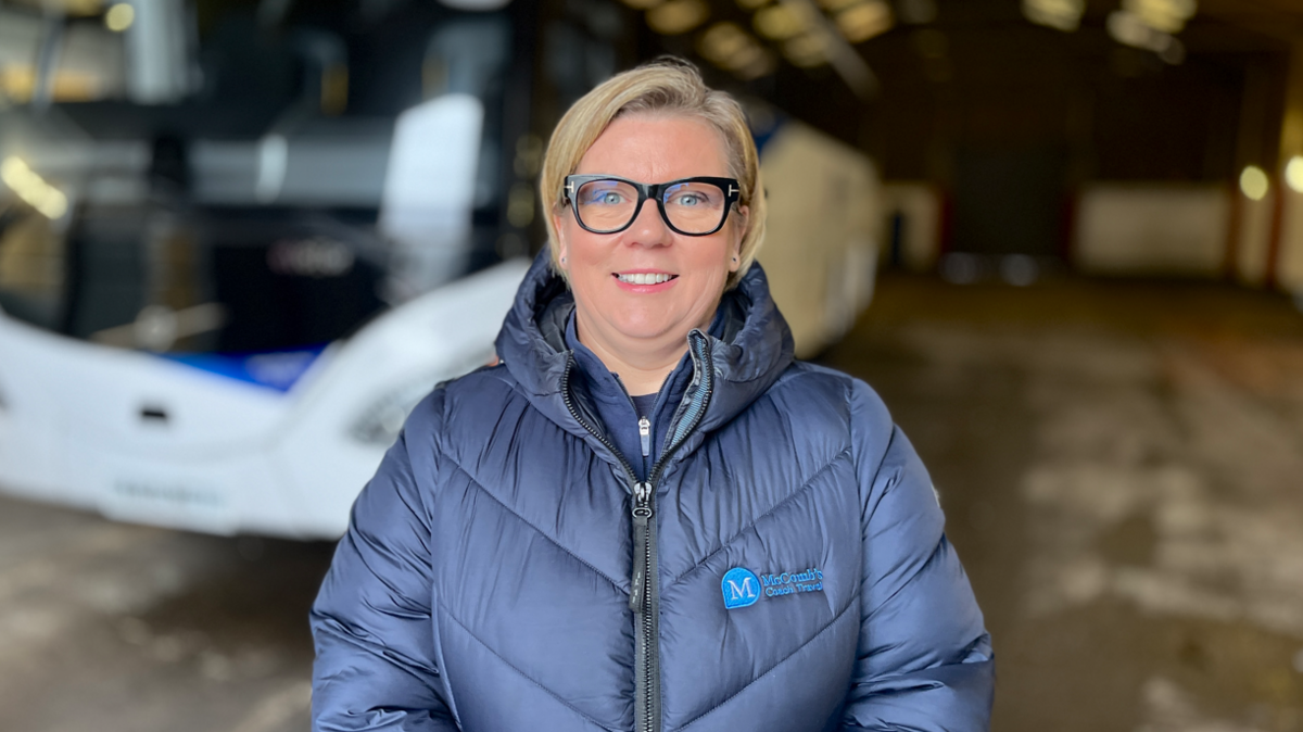 Caroline McComb, with blonde hair and glasses, wearing a blue jacket