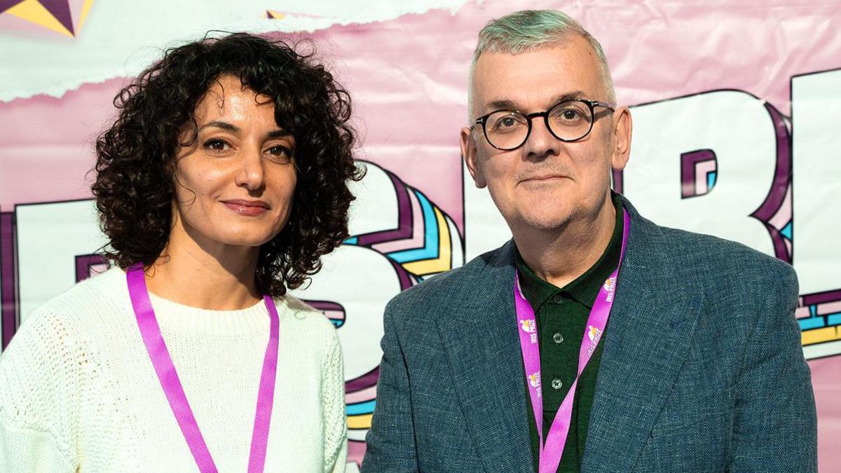 Dina Hamdan, winner of the Iris Prize 2024, standing next to the film festival director Berwyn Rowlands, with both smiling at the camera