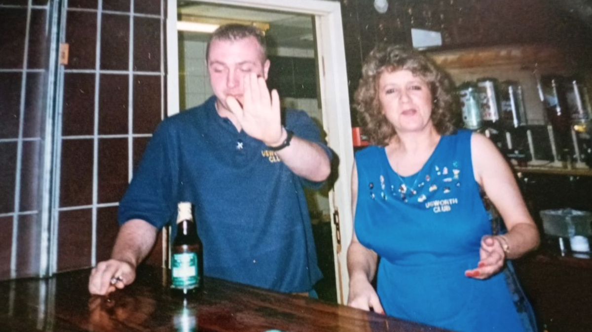 Denise Graham, wearing a blue Unsworth Club apron, with a man. behind the bar, with a man