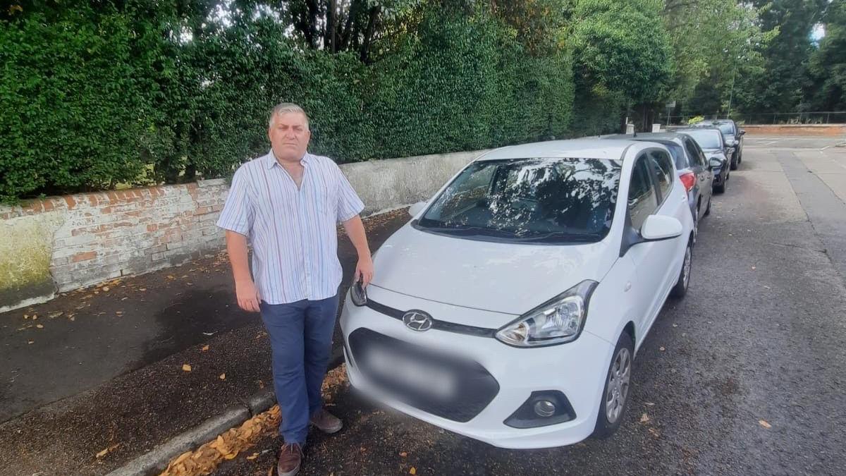A man stands by a white parked car
