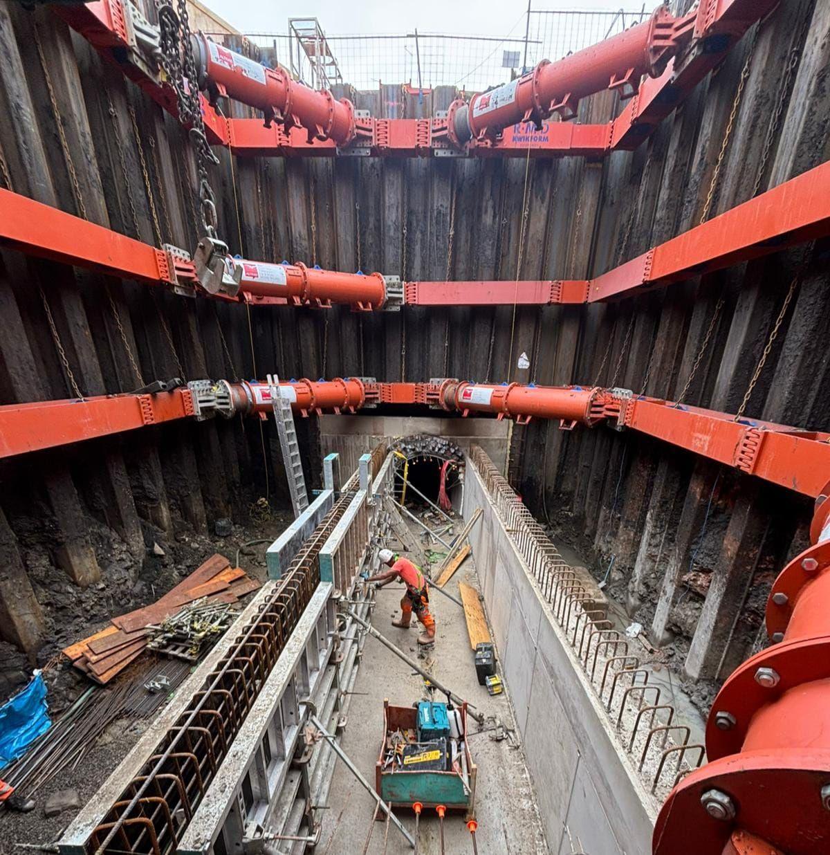 An engineer dressed in orange at the bottom of the 14 metre deep sinkhole fixes steel and concrete girders 