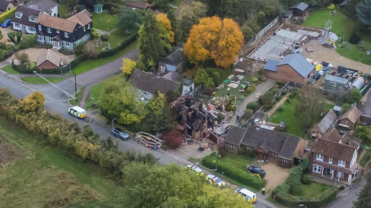 A photo taken by a drone of Cleat Hill after the explosion. Police cars are parked along the street where the destroyed remains of a house can be seen.