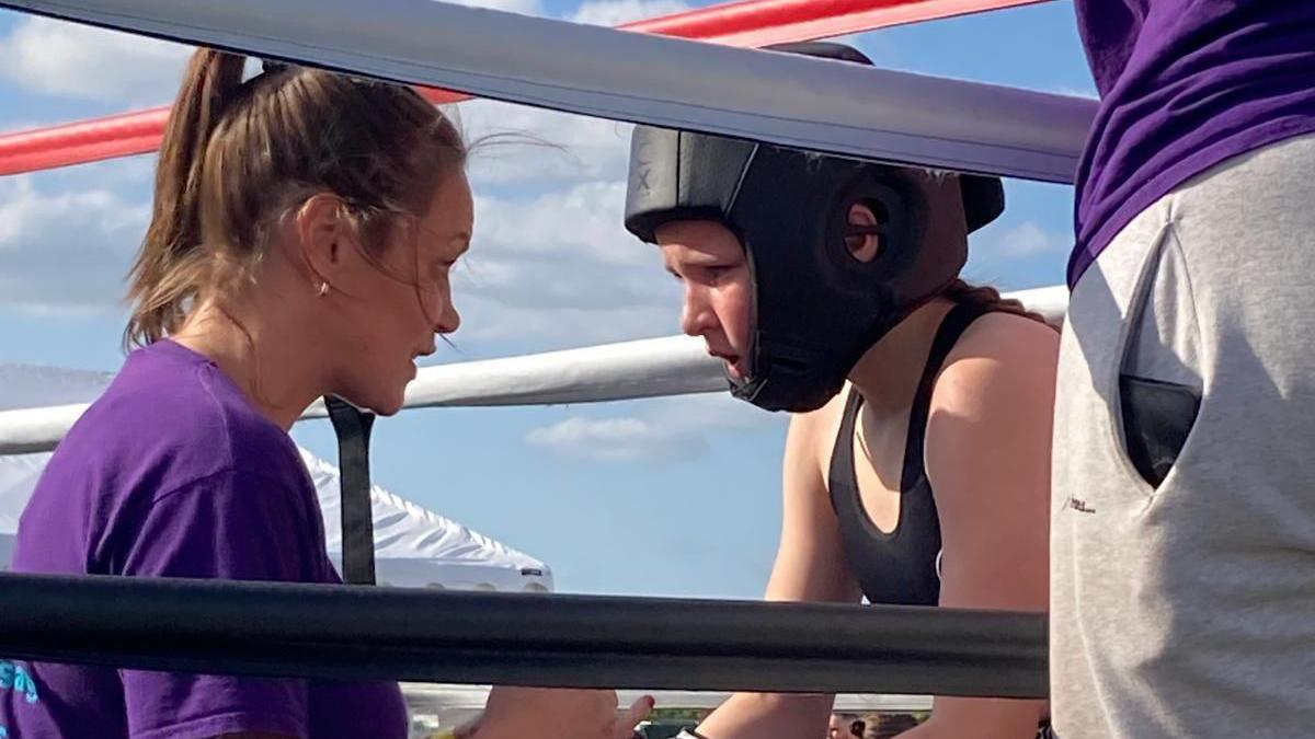 Michelle Minaides standing in the corner of the ring with one of her daughters coaching her. They are both looking into each other's eyes.