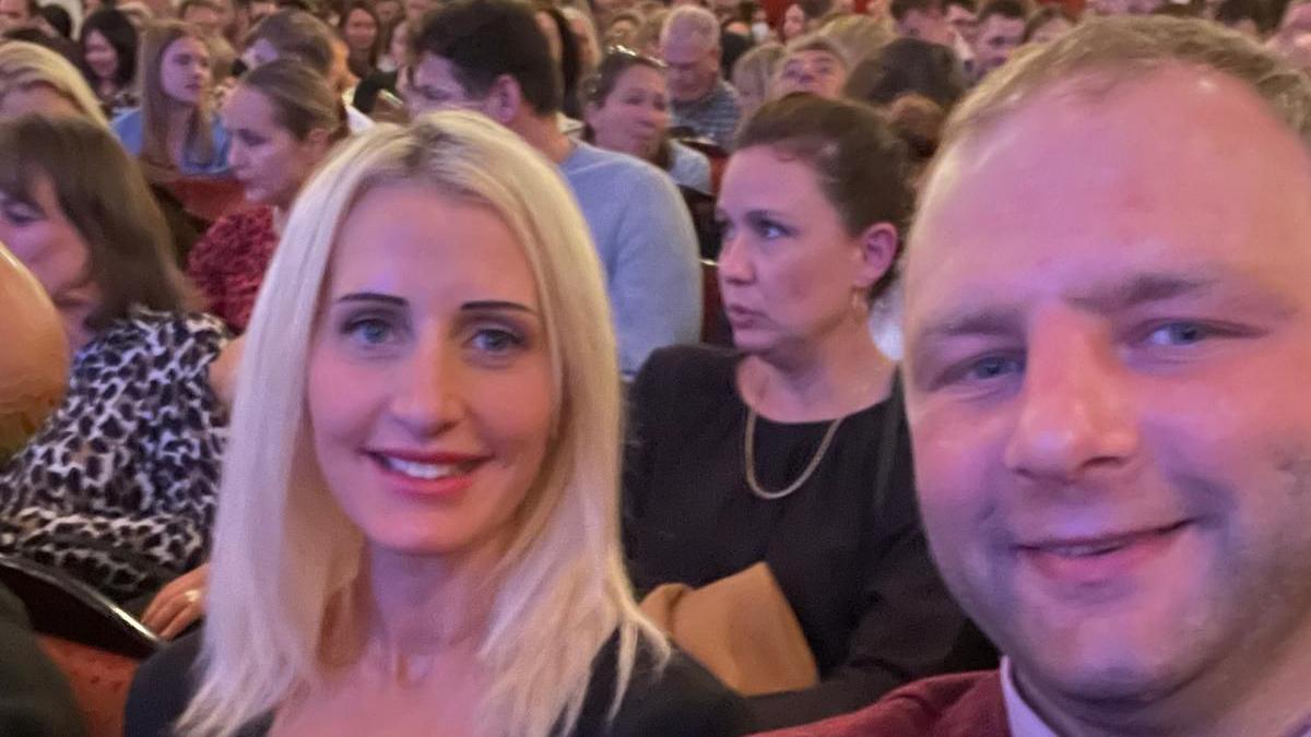 A woman and man sit in the audience at a theatre