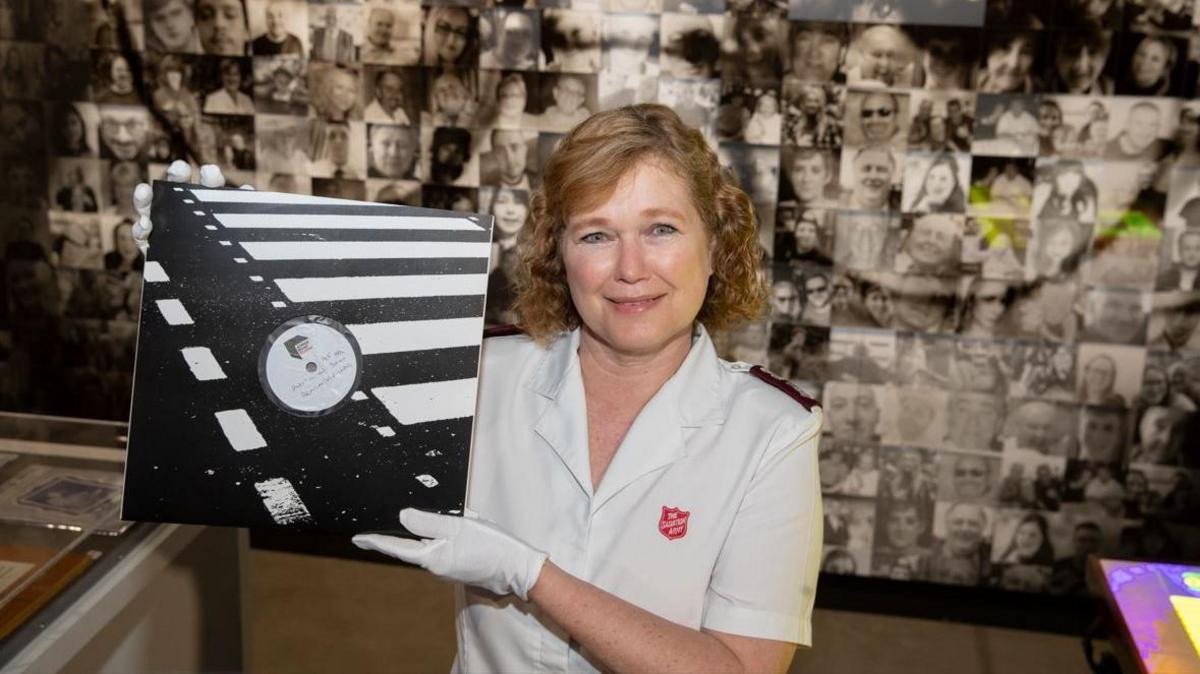 Mission Director of Strawberry Field, Major Kathy Versfeld holding the vinyl