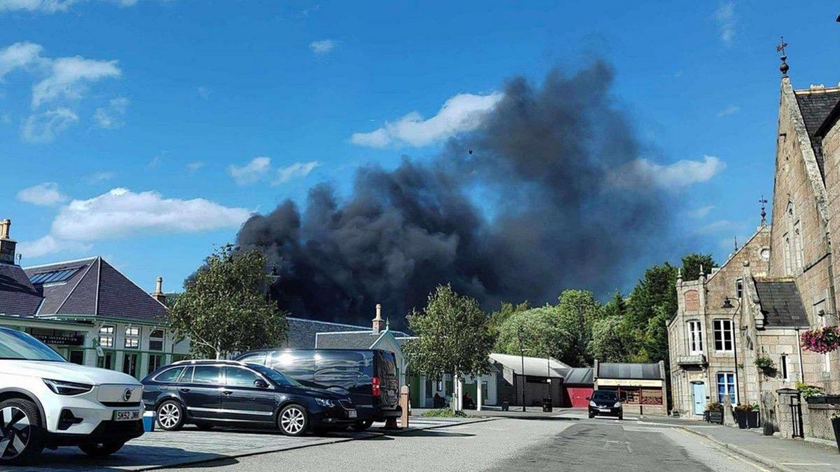 Wide shot of Ballater's Station Square, overshadowed by a large plume of black smoke from the house fire in nearby Swann Place.