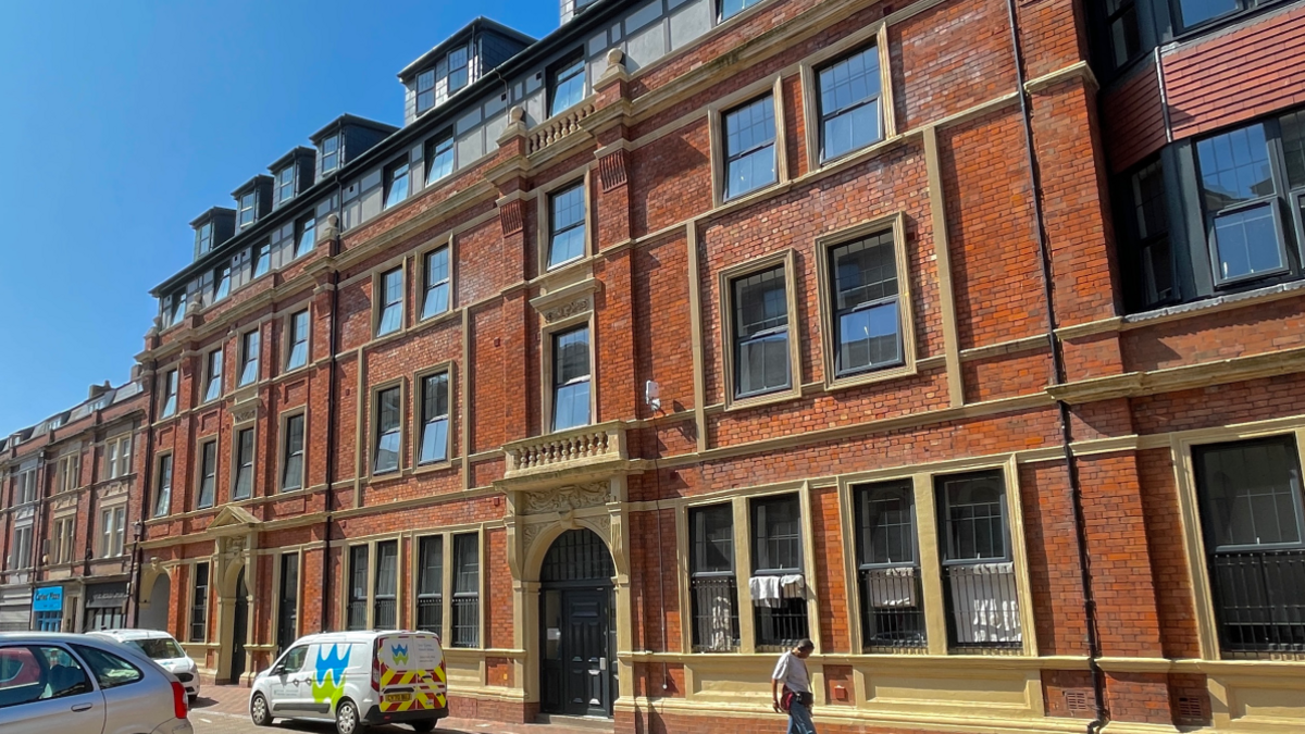 Bay Chambers, a four-storey redbrick building, with many windows at the front, and vehicles on the road outside