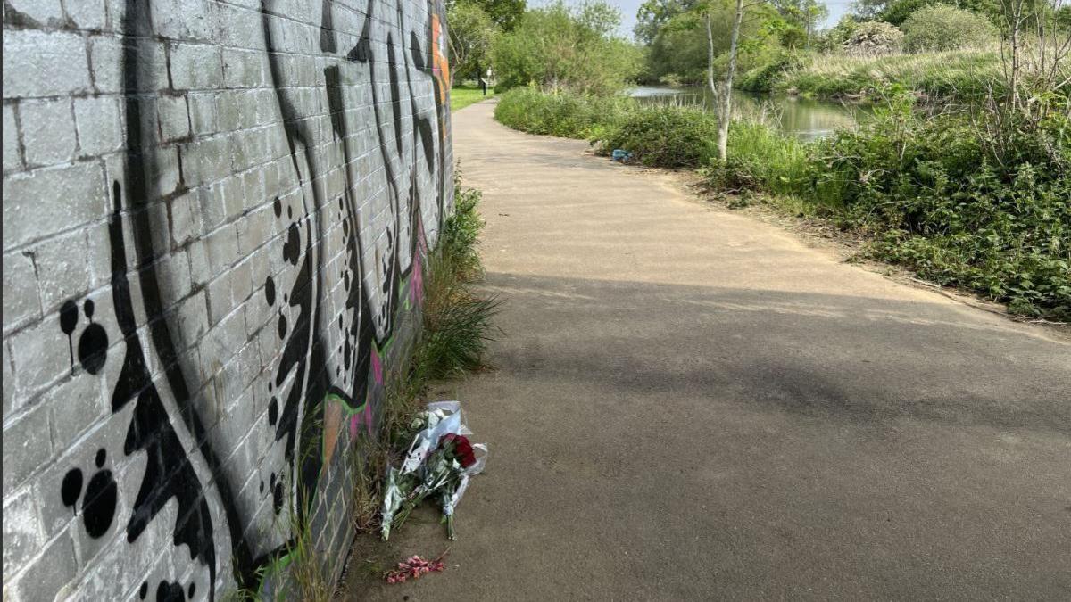 Flowers left in tribute on river path