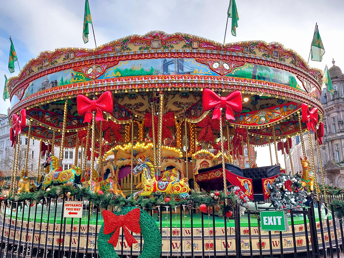 A fairground ride in Birmingham. Colourful horses line up on the carousel on the end of gold-painted poles