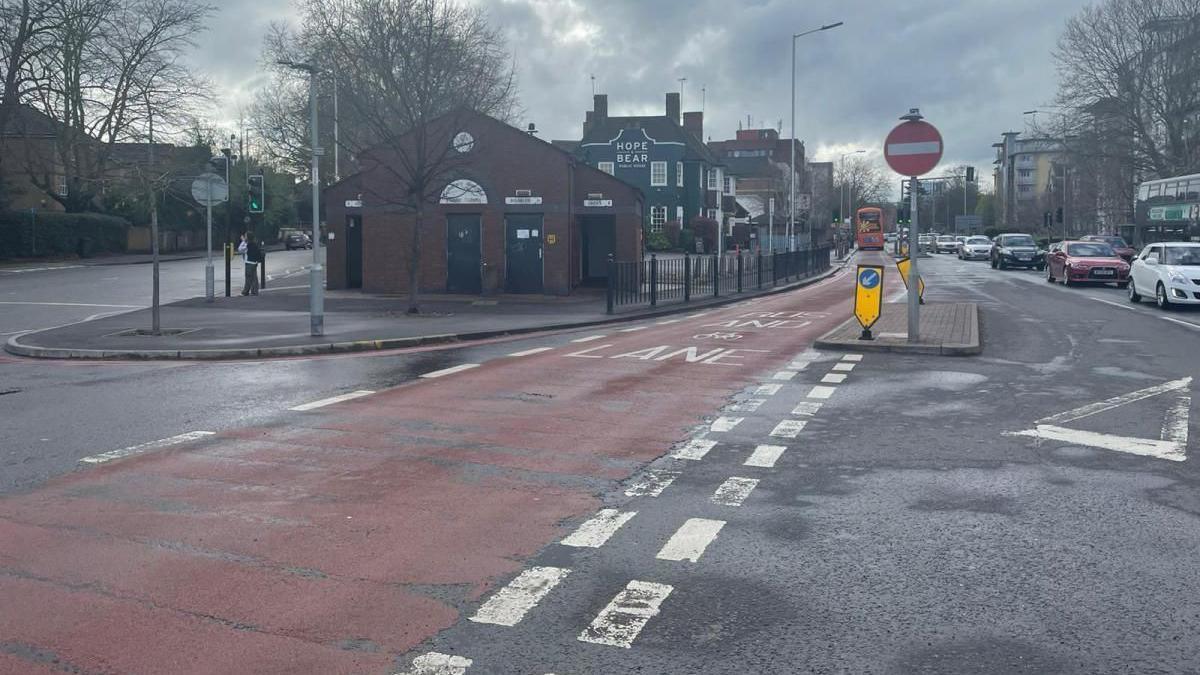 red bus lane next to pub called Hope and Bear