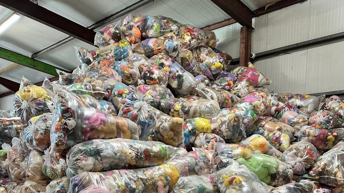 A huge pile of clear plastic bags filled with colourful toys in a warehouse