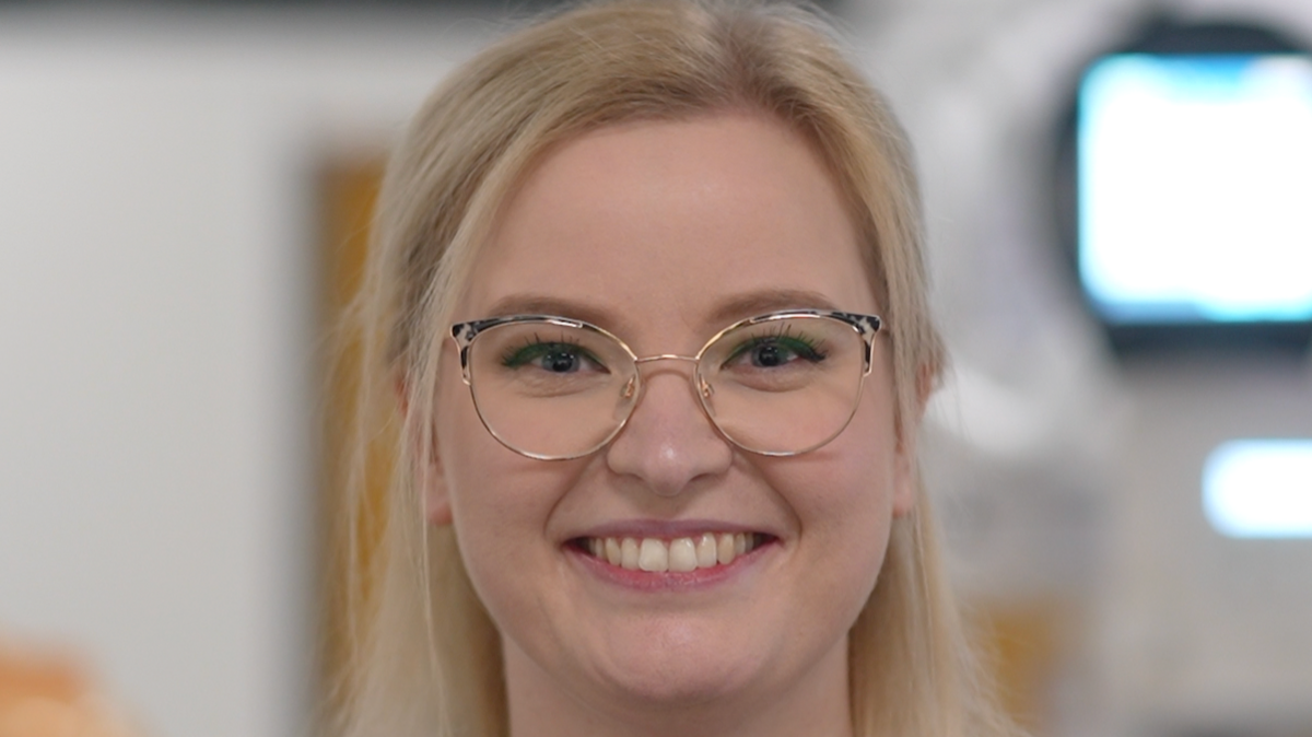 Ms Shuttlewood-Limb smiles at the camera. She has long blonde hair which has been partly tied back behind her head. She is also wearing glasses.