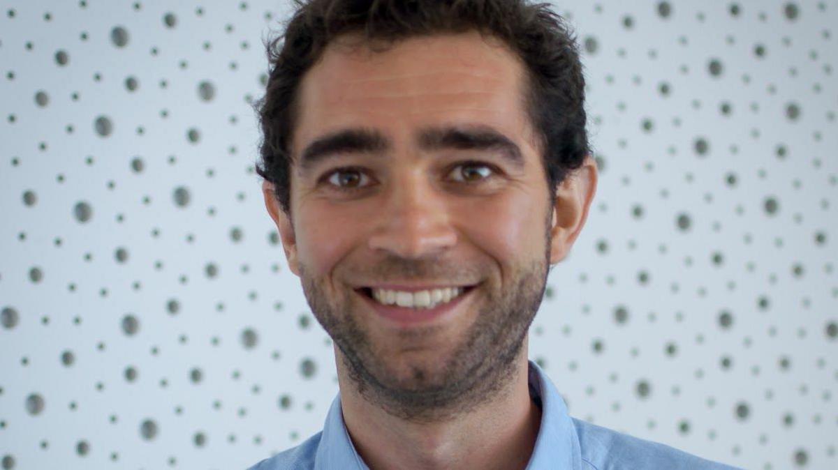 Dr Tommaso Reggiani wearing a blue shirt and smiling at camera