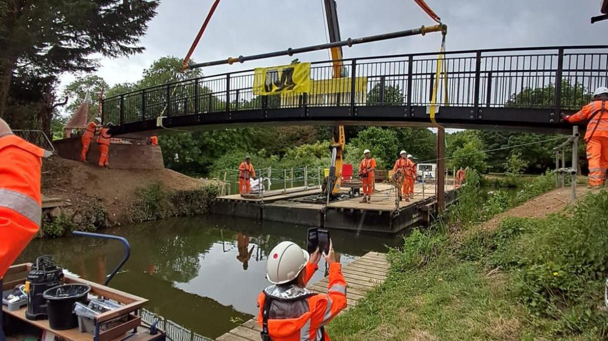 The footbridge is lowered into position by crane