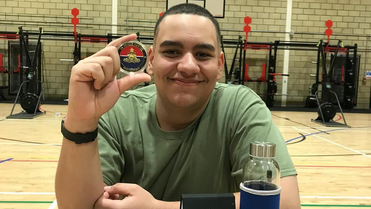 Harley holding up a medal, wearing a green t-shirt