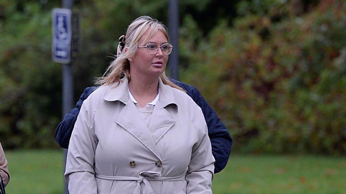 Julie Ann McIlwaine pictured wearing a beige coloured coat, she has blonde hair and is wearing classes. She looks to her left as she walks towards the camera.