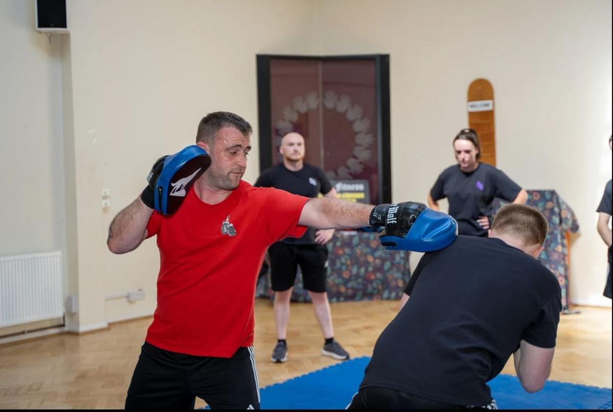 A man in a red t shirt spars with an opponent