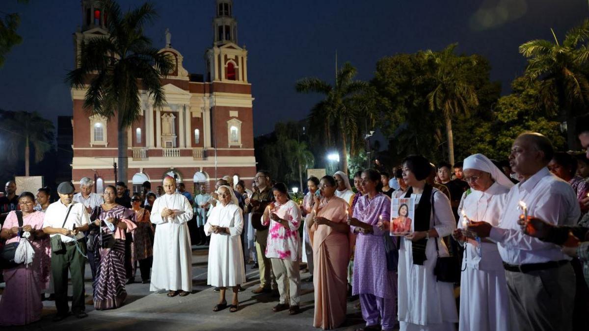 People hold candles as they attend a vigil for the victims of an Air India plane crash in New Delhi