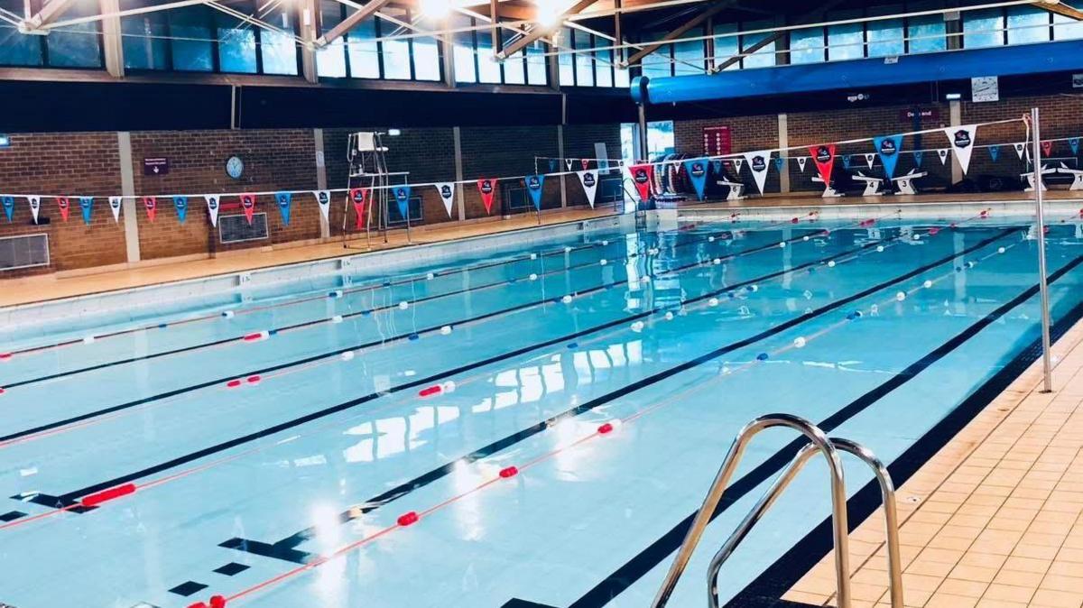 The six-lane swimming pool at the Brentwood Centre. Red, white and blue bunting is suspended over the water.