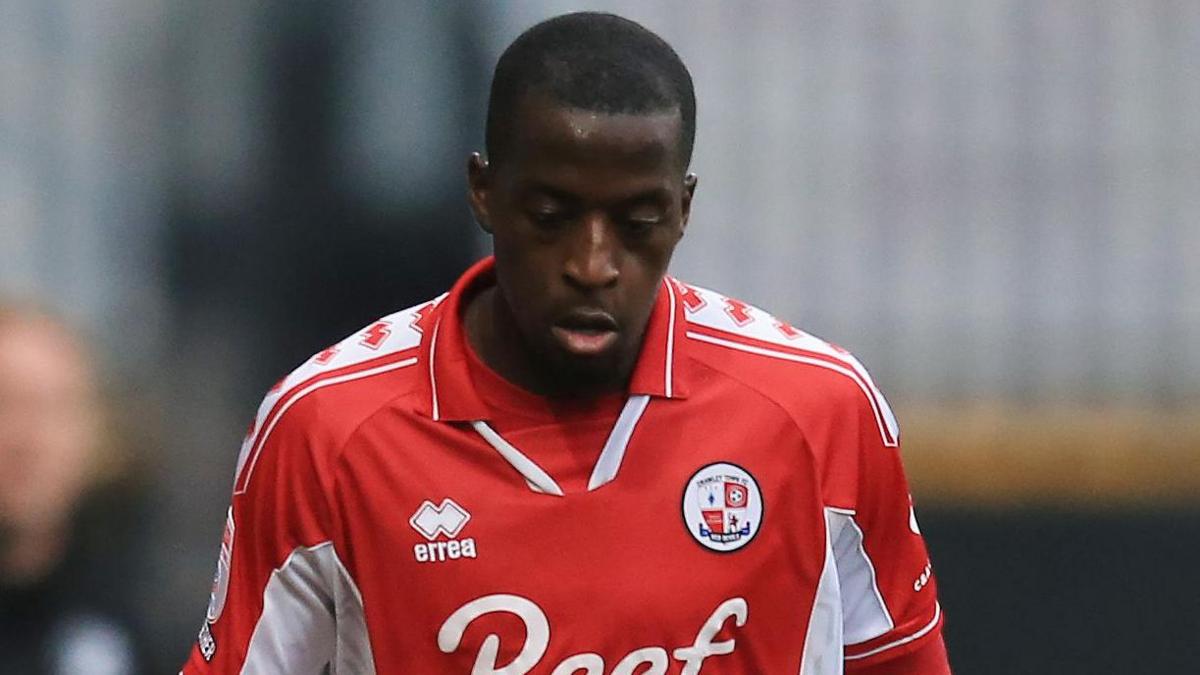 Ade Adeyemo in a red Crawley shirt looks down