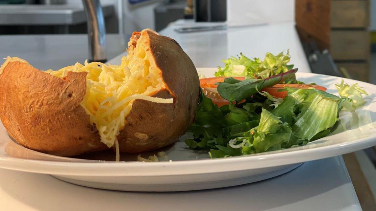 Close up of a cheesy jacket potato and a salad garnish